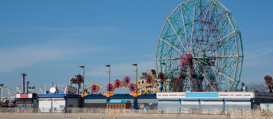 Coney Island boardwalk with iconic Ferris wheel and rides.