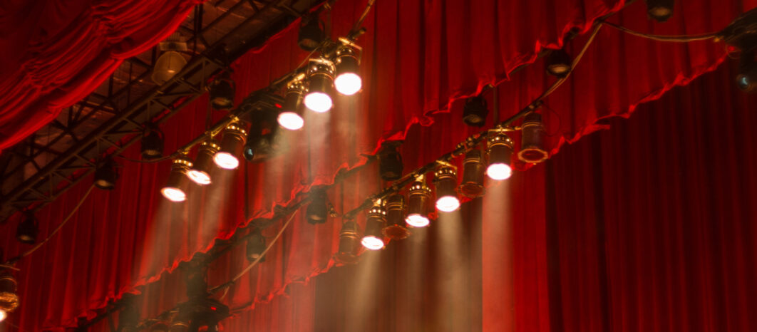 Red theater curtains with spotlights shining on stage.