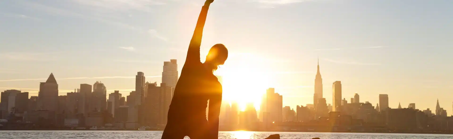 sunrise image with the city skyline and a woman doing an overarm stretch.