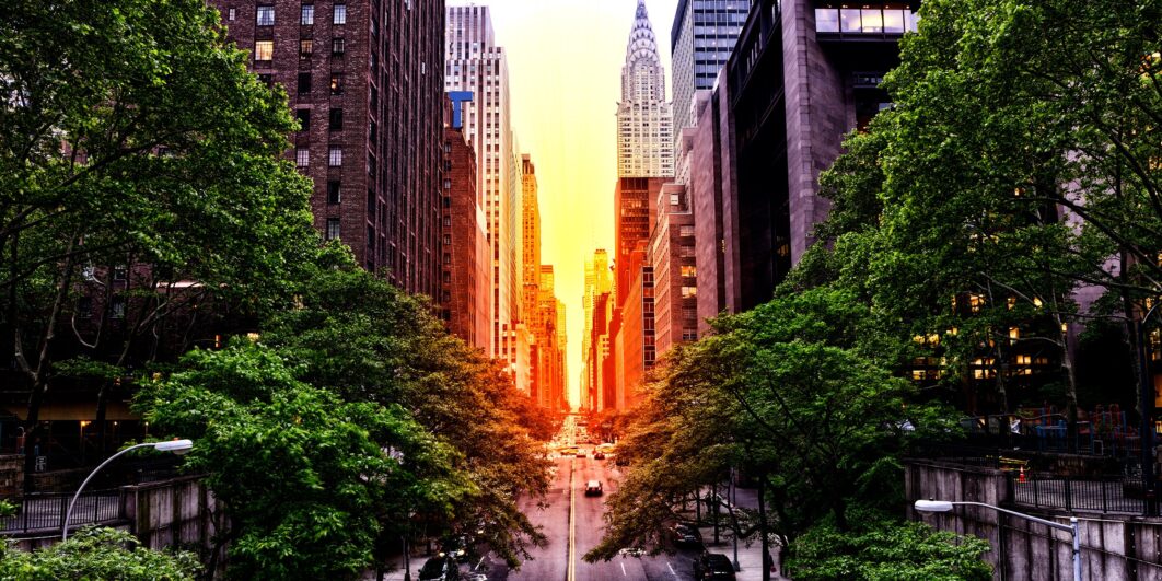 Urban street at sunset with Chrysler Building in distance.