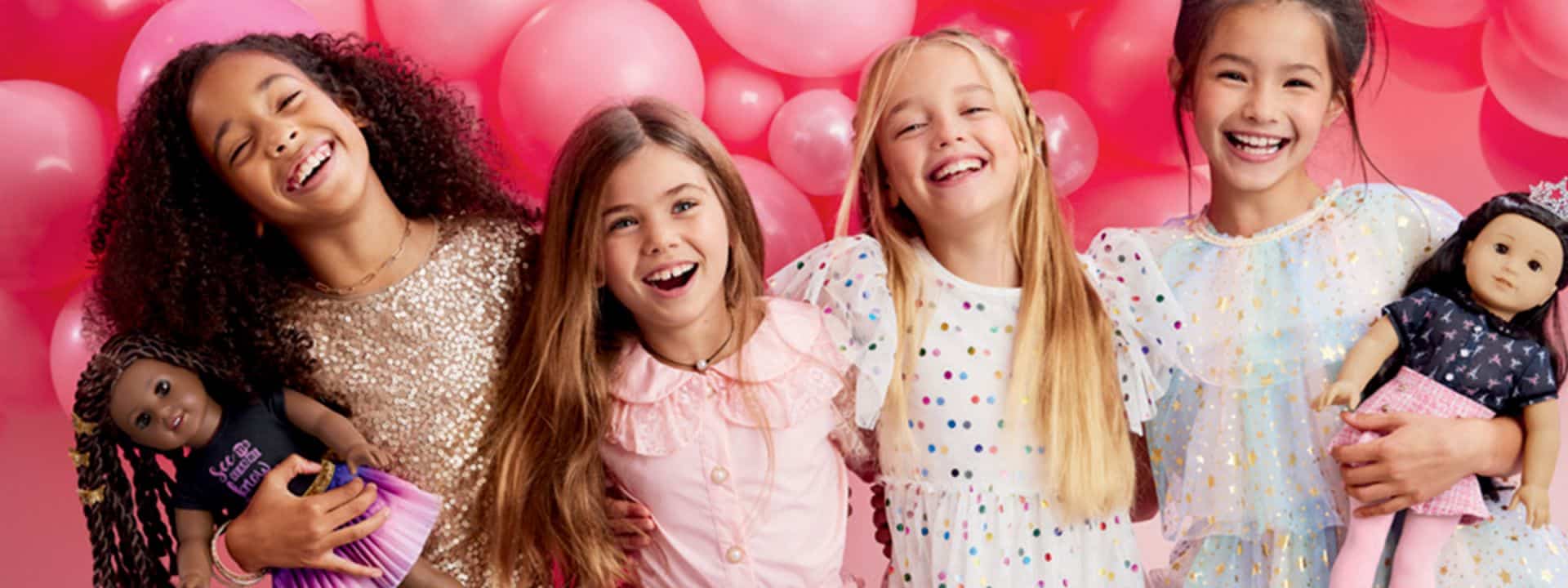 Four kids smiling for the photo with pink balloons behind them.