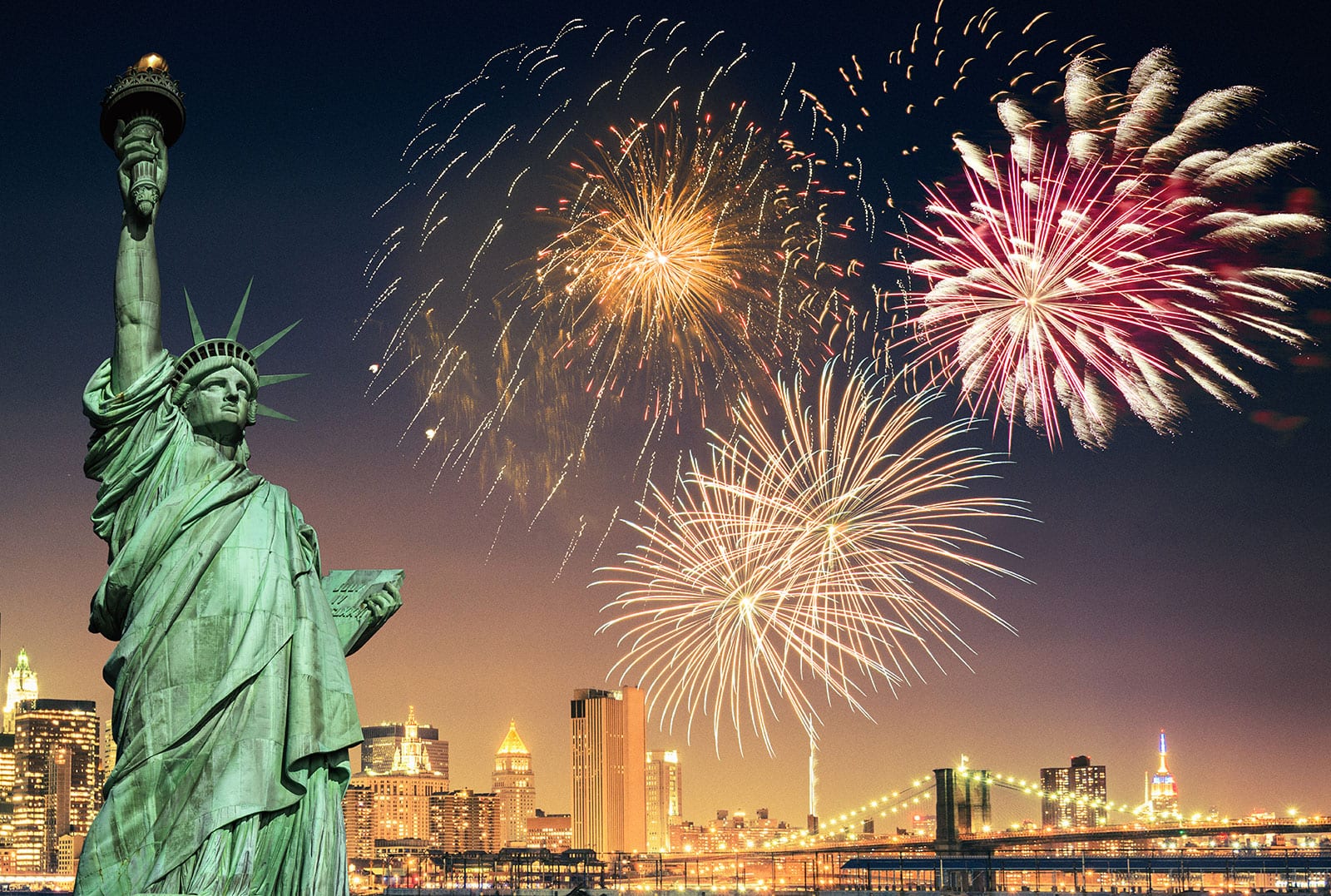 Statue of Liberty with colorful fireworks illuminating the night sky.