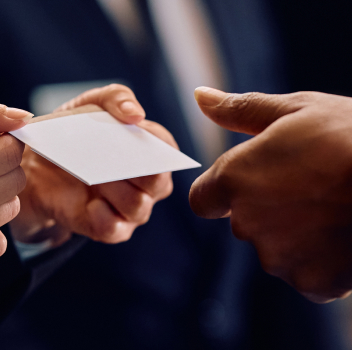 Business card exchange between two hands in formal setting.