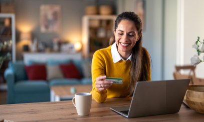 Woman sitting at her laptop desk and paying for a hotel room with her card.