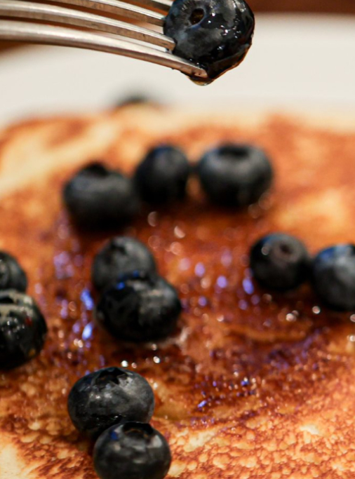 Pancakes topped with fresh blueberries and syrup drizzle.