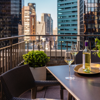 Luxury rooftop terrace with wine and city skyline views.