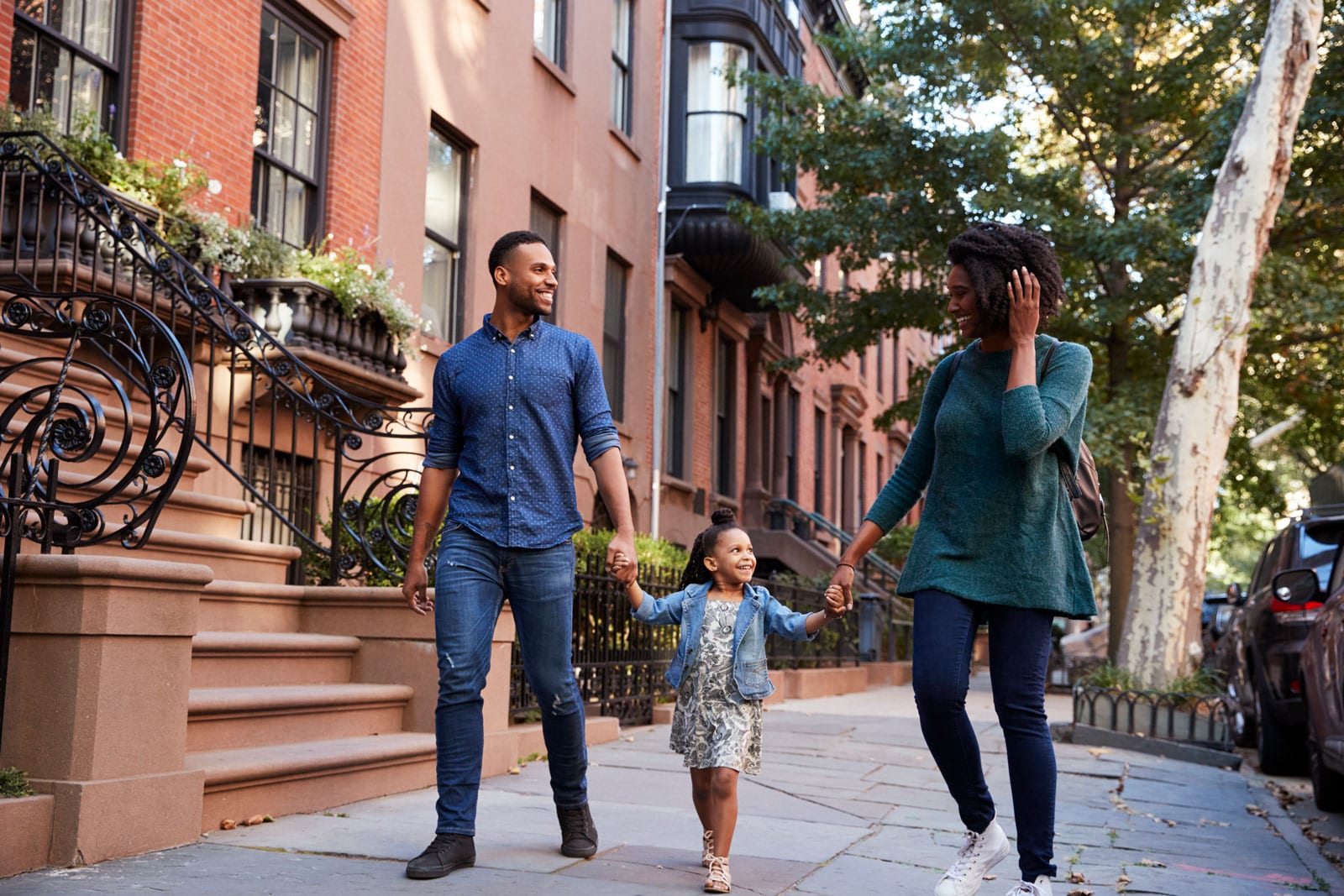 A couple with a child between them and holding their hands.