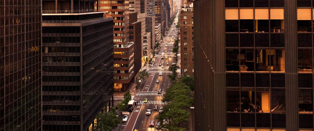 Aerial view of a busy New York City street at sunset with tall buildings.