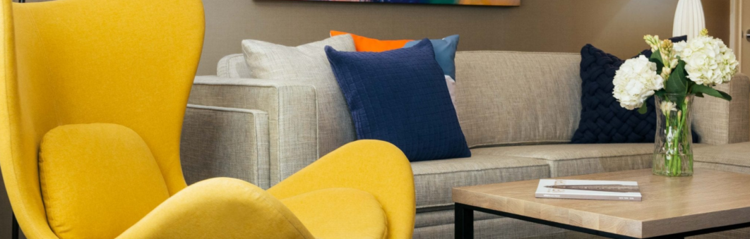 Modern hotel room with yellow chair and blue sofa.