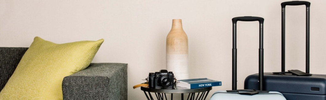 Close-up of luggage, travel book, and camera on a table.