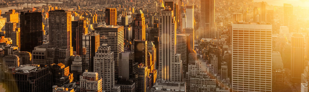 New York City skyline at sunset, golden light over buildings.