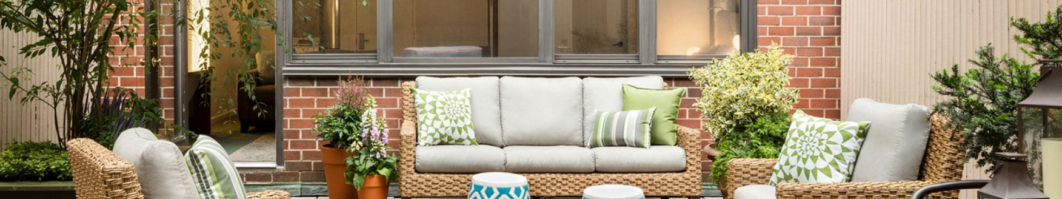 Cozy outdoor seating area with a brick wall and green plants.