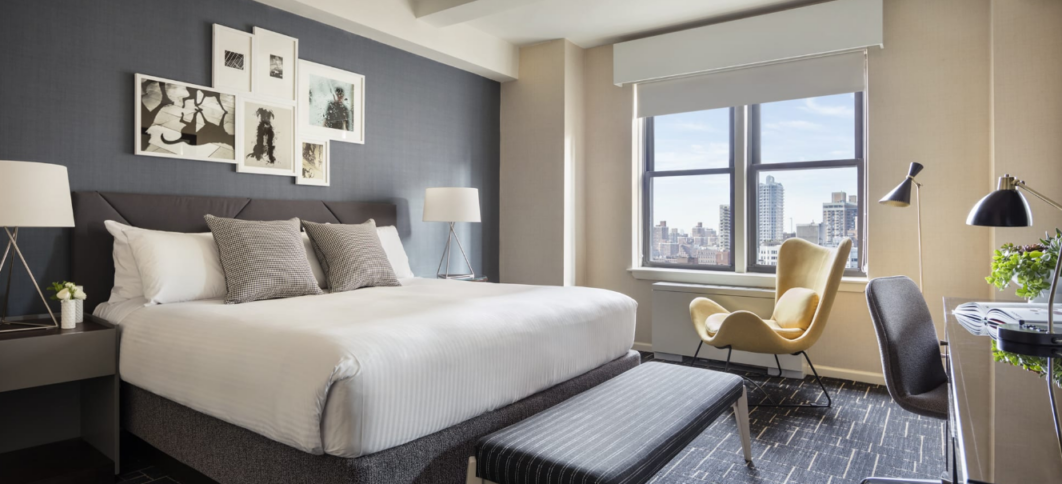 Modern hotel room with a king-size bed, stylish decor, and city view.