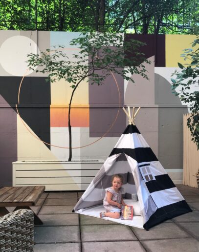 A kid playing in a tent at the cozy outdoor terrace.