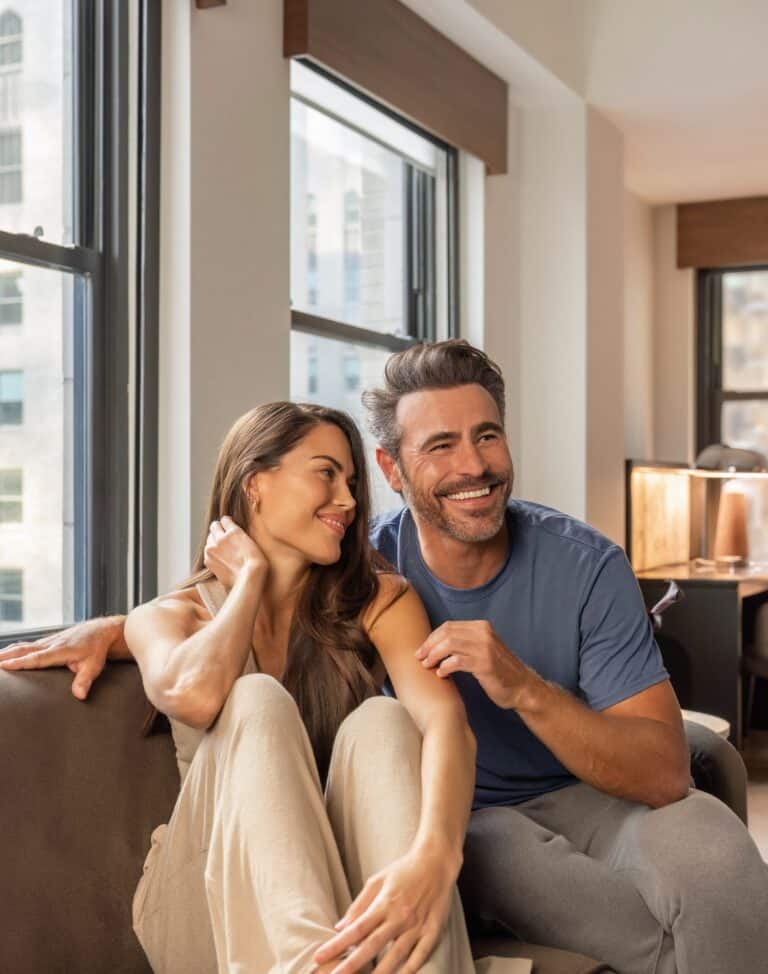 Couple on a couch in their hotel room enjoying a cozy stay.