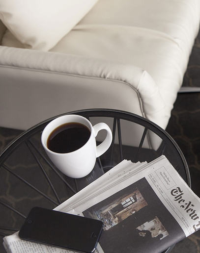 Cup of coffee on table with newspaper and smartphone.