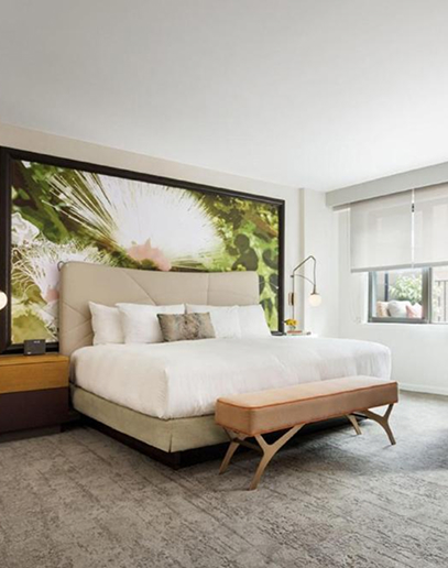 Luxury hotel bedroom with king bed and nature artwork.