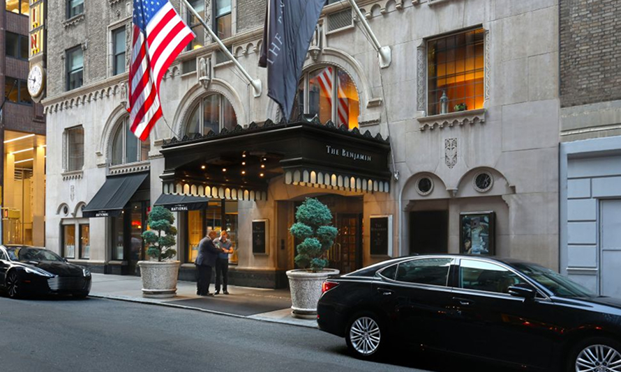 Hotel entrance with a US and Sonesta flag above it.